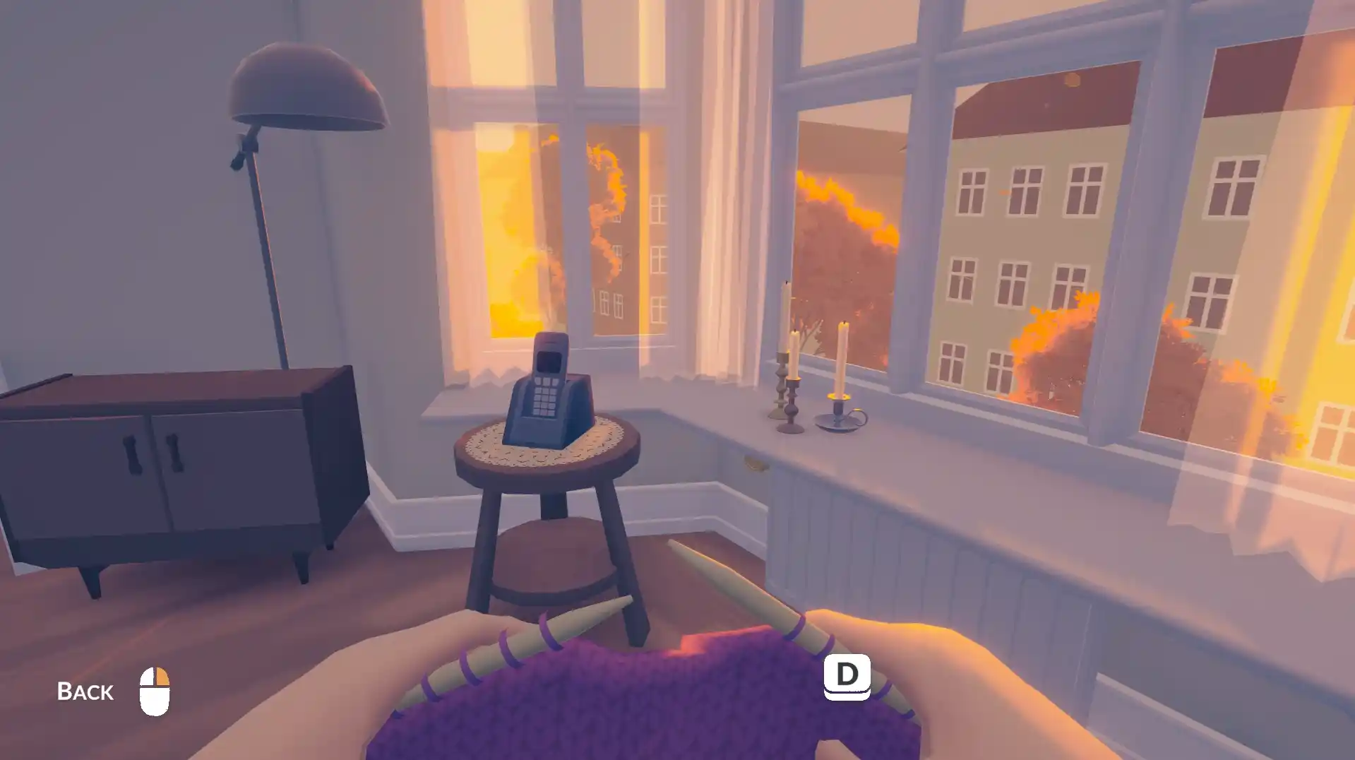 Screenshot di As Long as You’re Here che mostra le mani che lavorano a maglia davanti a una finestra con luce calda e palazzi sullo sfondo.