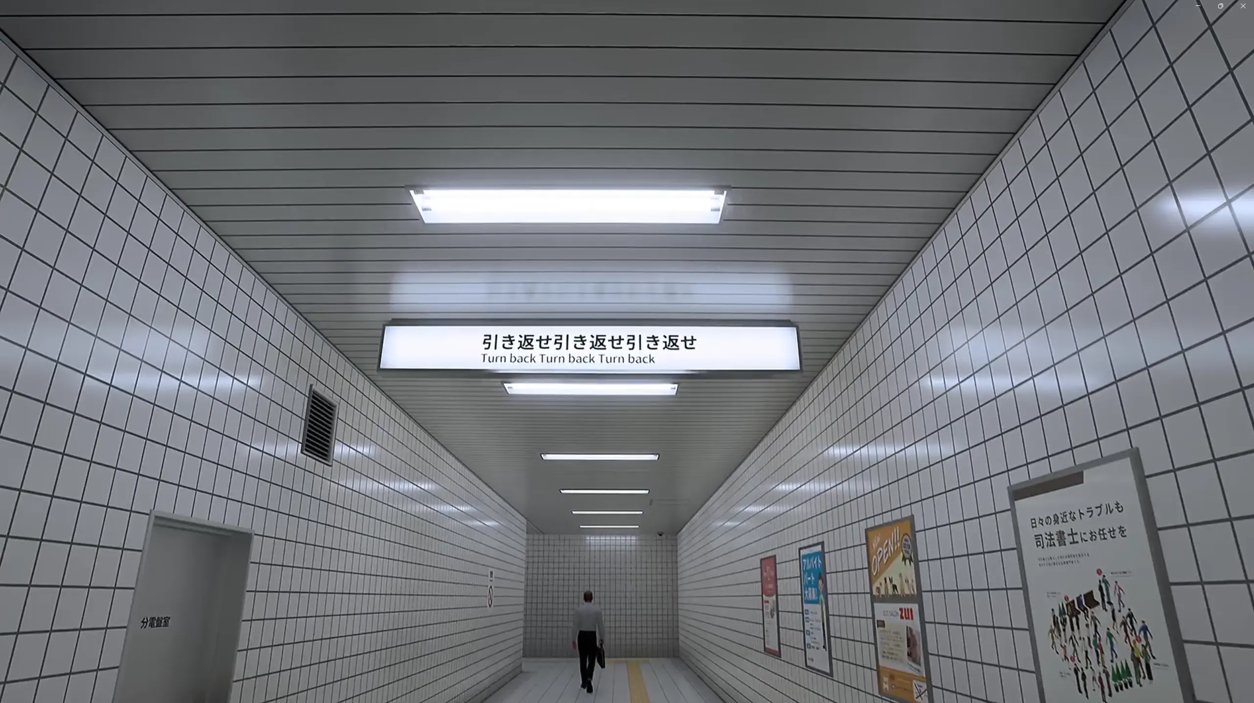 Corridoio piastrellato con un cartello luminoso sul soffitto che indica “Turn back”.