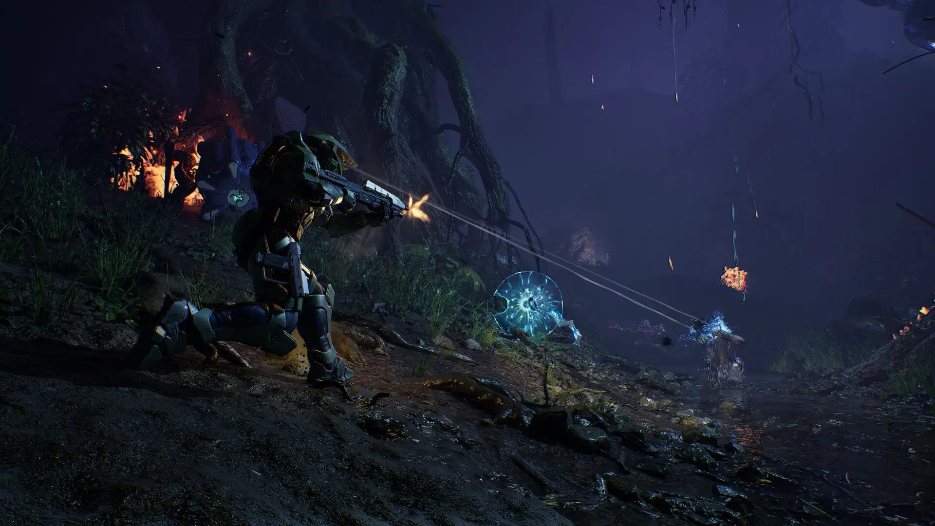 Master Chief accovacciato in una palude buia spara con il fucile d'assalto verso destra, illuminando l'ambiente con le scie dei proiettili.